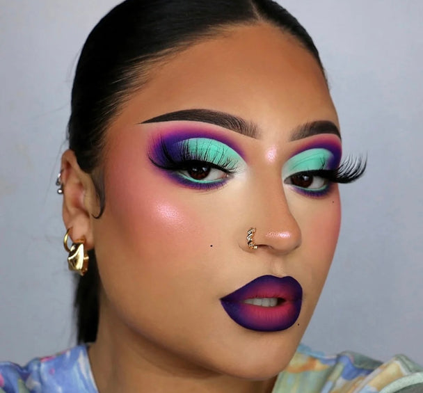 A closeup of a beautiful black woman wearing Game Tight Premium 3d Mink - 25mm false eyelashes with vibrant lipstick and bold eyeshadow.