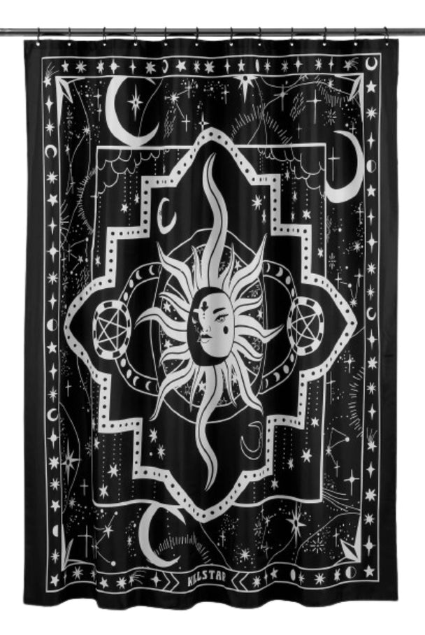 A black and white shower curtain with a white sun hanging on a shower rod.