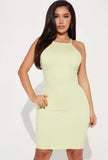 A woman wearing a lime green mini dress with spaghetti straps.