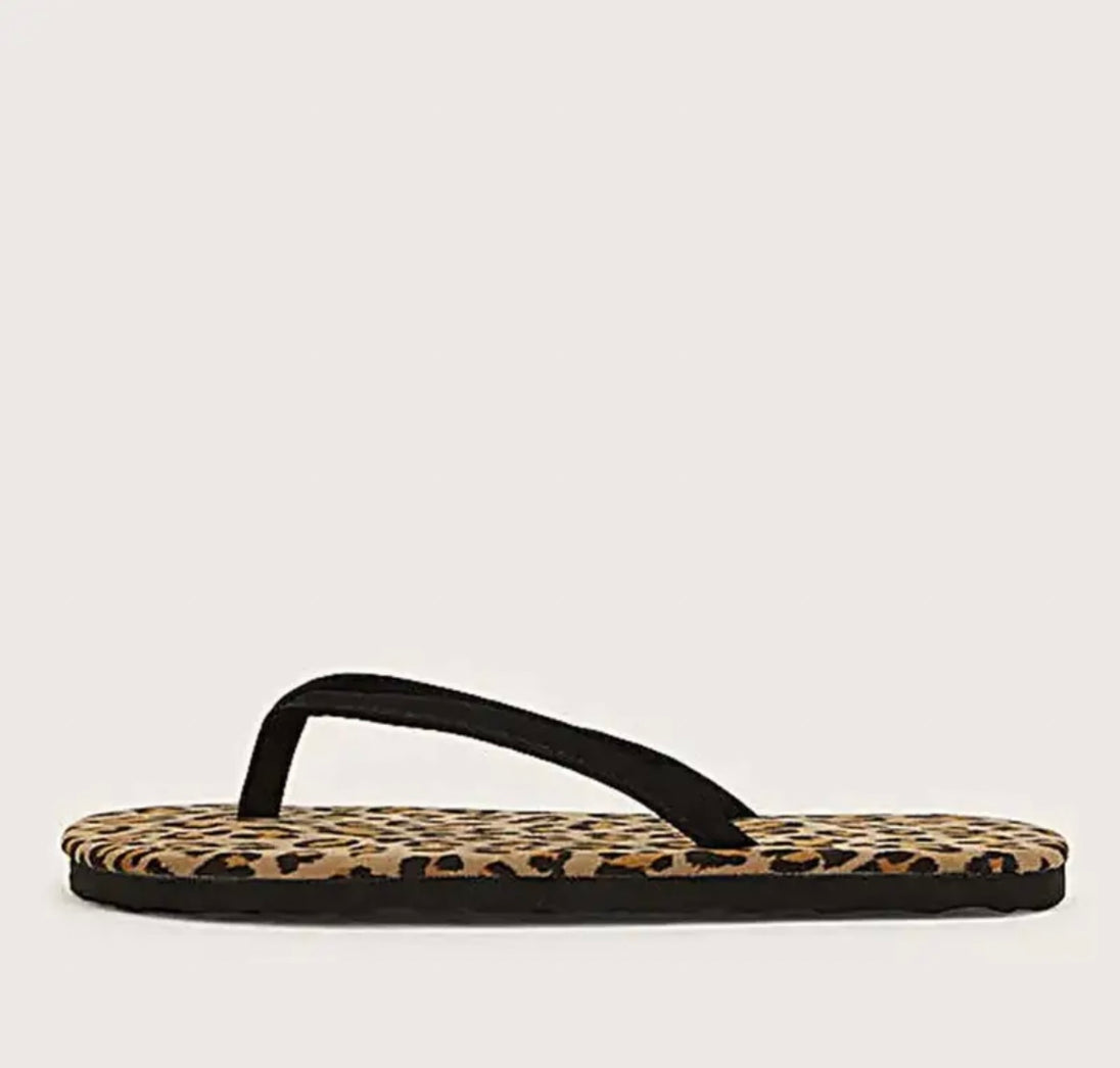 A close up of one leopard patterned flip flop.