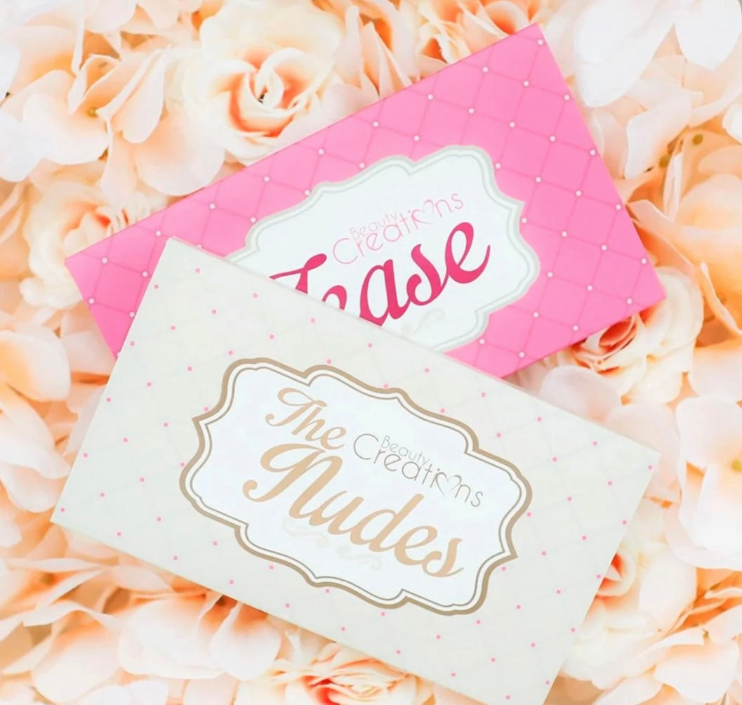A close-up of two makeup palette boxes laying on a bed of roses.