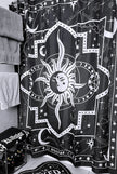 A black and white shower curtain with a white sun hanging on a shower rod in a bathroom.