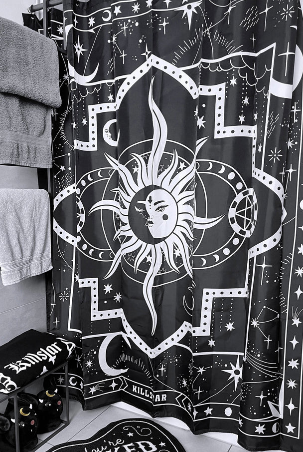 A black and white shower curtain with a white sun hanging on a shower rod in a bathroom.